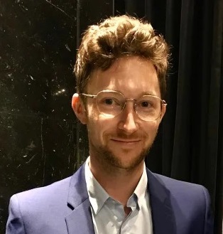 David Ellis wearing a white shirt, blue jacket and glasses
